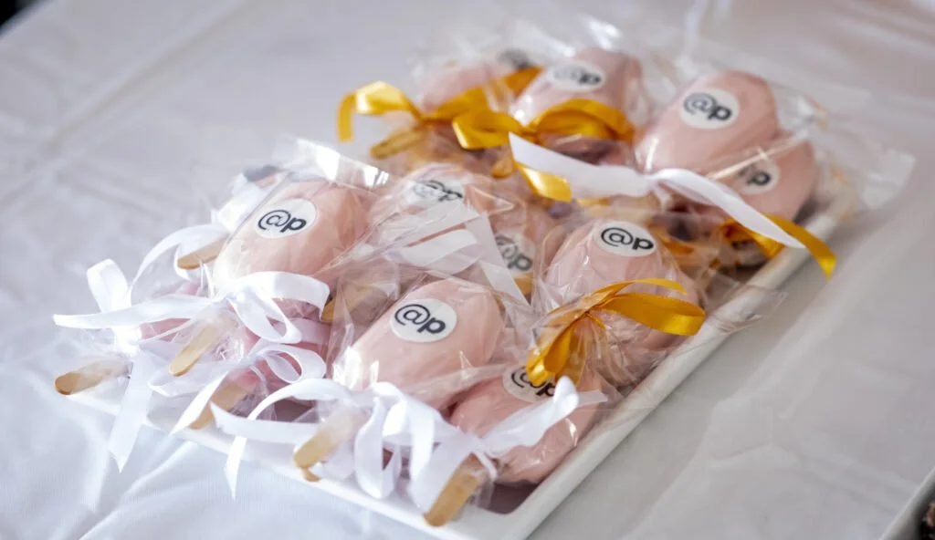 Decorated gift boxes with white and gold ribbons arranged on a white tray, branded with @p logo