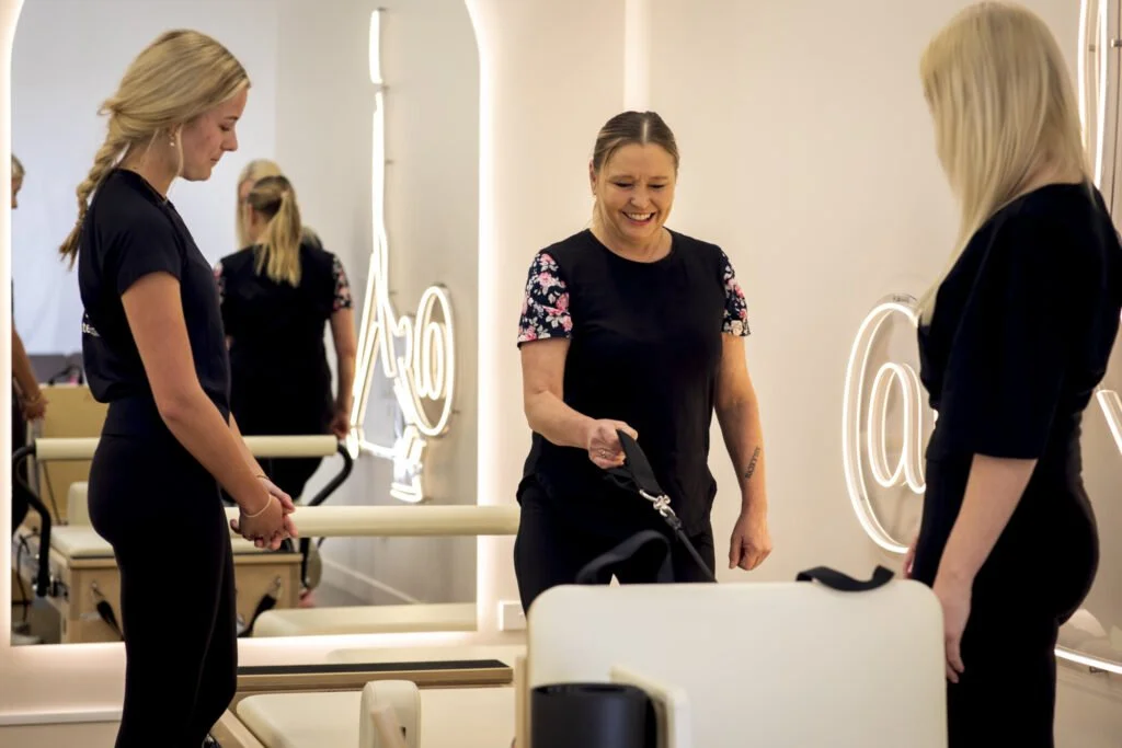 Women chatting in a modern pilates studio with neon signs and exercise equipment